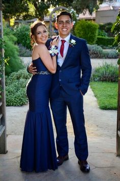 a man and woman in formal wear posing for a photo together at an outdoor venue