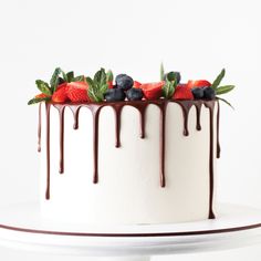 a white cake topped with berries and chocolate drizzle