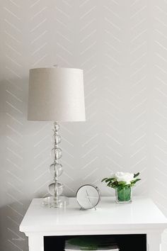 a white table with a lamp and vase on it