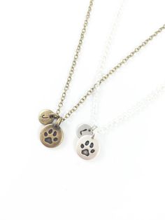 two necklaces with dog paw prints on them, one is silver and the other is gold