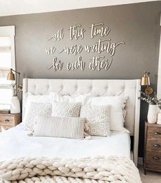 a white bed sitting under a metal wall sign