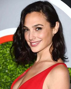 a woman in a red dress smiling at the camera with her hair pulled back and shoulder length