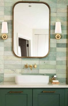 a bathroom with green cabinets and a large mirror above the sink in front of it