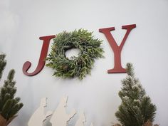 a christmas wreath is hanging on the wall next to two wooden letters that spell joy