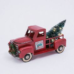 an old red truck with a christmas tree in the back