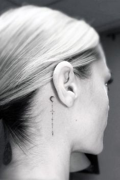 a woman's ear with a small tattoo on her left side behind the ear