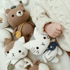 a baby is laying next to several crocheted stuffed animals