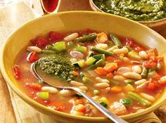 a yellow bowl filled with beans and veggies on top of a wooden table