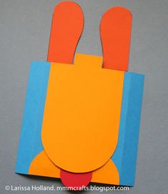 an orange and blue piece of paper with scissors sticking out of it's back