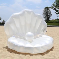 an inflatable shell on the beach with two balls floating out of it's shell