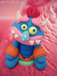 a blue and orange toy sitting on top of a pink surface with its mouth open