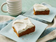 two slices of carrot cake with frosting on white plates