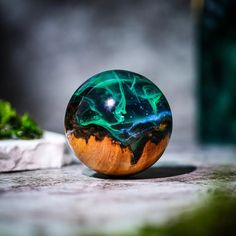 a glass ball sitting on top of a table next to a potted green plant