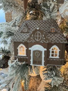 a brown and white house ornament hanging from a christmas tree