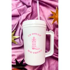 a white coffee cup with a straw in it on a pink blanket next to gold stars