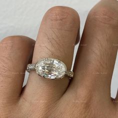 a woman's hand with a diamond ring on top of her finger and an engagement band