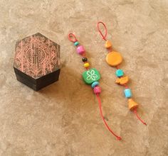 a wooden box with beads and a necklace on the ground next to an ornament