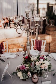 a candelabra with flowers and candles on top of a table at a wedding reception