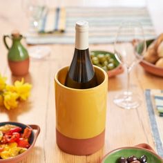 a bottle of wine sitting on top of a wooden table next to plates and bowls