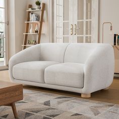 a white couch sitting on top of a hard wood floor next to a wooden table