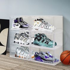 four clear acrylic boxes with different types of shoes in them next to a basketball