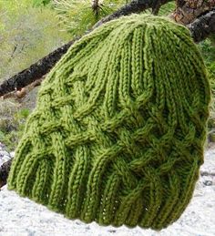 a green knitted hat sitting on top of a tree branch