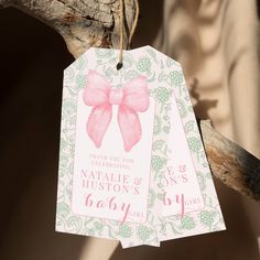 two tags with pink bows hang from a tree branch