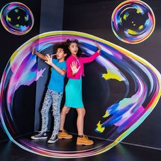 two children standing in front of a wall with soap bubbles