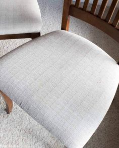 an upholstered chair sits on carpeted floor next to a wooden armless chair