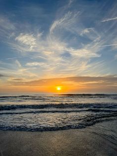 the sun is setting over the ocean with clouds in the sky and waves on the beach