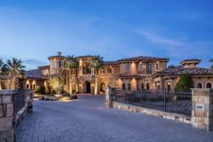 a large house with lots of windows and palm trees in the front yard at dusk