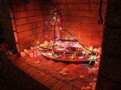 a boat is lit up with christmas lights in the brick wall next to some rocks