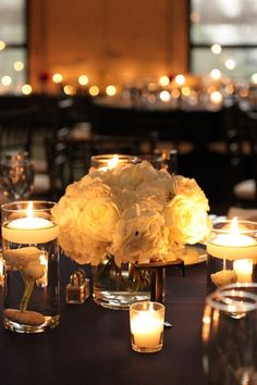 the centerpieces are filled with white flowers and lit candles in glass vases