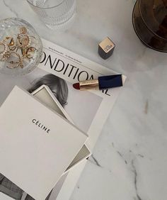 the contents of a beauty product displayed on a marble countertop next to an empty magazine