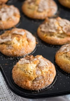 freshly baked muffins sitting in a black tray on a tablecloth covered table