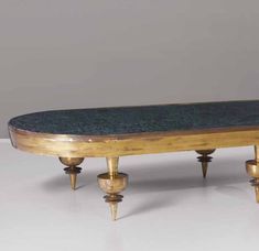 an antique wooden table with three brass legs and a green marble top, sitting on a white surface