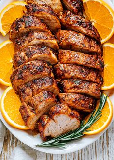 sliced pork and oranges on a white plate