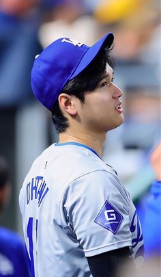 a baseball player wearing a blue hat and looking off to the side with his head tilted