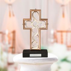 a metal cross on top of a white pedestal