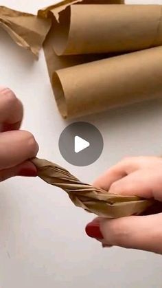 two hands are holding a piece of brown paper and wrapping it around the other hand