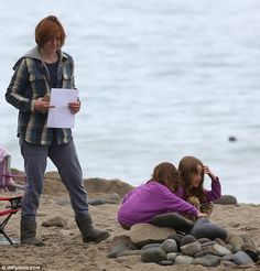 two women are sitting on the beach and one woman is holding a piece of paper