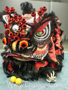 an elaborate dragon mask sitting on the ground next to some oranges and two black birds