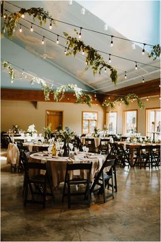 tables and chairs are set up for a wedding reception with lights strung from the ceiling