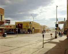 an empty city street with people walking on the sidewalk