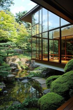 the inside of a house that is surrounded by trees and rocks with a small pond in front of it