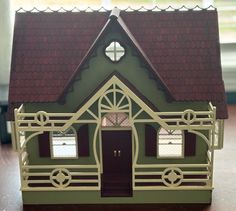 a green doll house with red roof and white trim