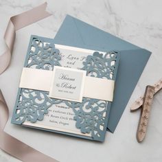 a blue and white wedding card with a pair of scissors next to it on a table