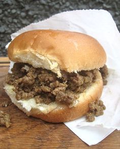 a close up of a sandwich with meat on it sitting on top of a wooden table