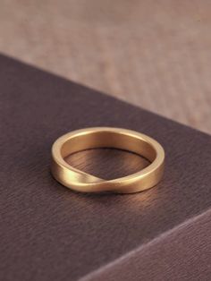 a gold wedding ring sitting on top of a book with a brown cover behind it