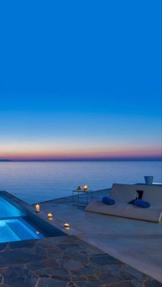 an outdoor swimming pool next to the ocean with candles lit up in front of it